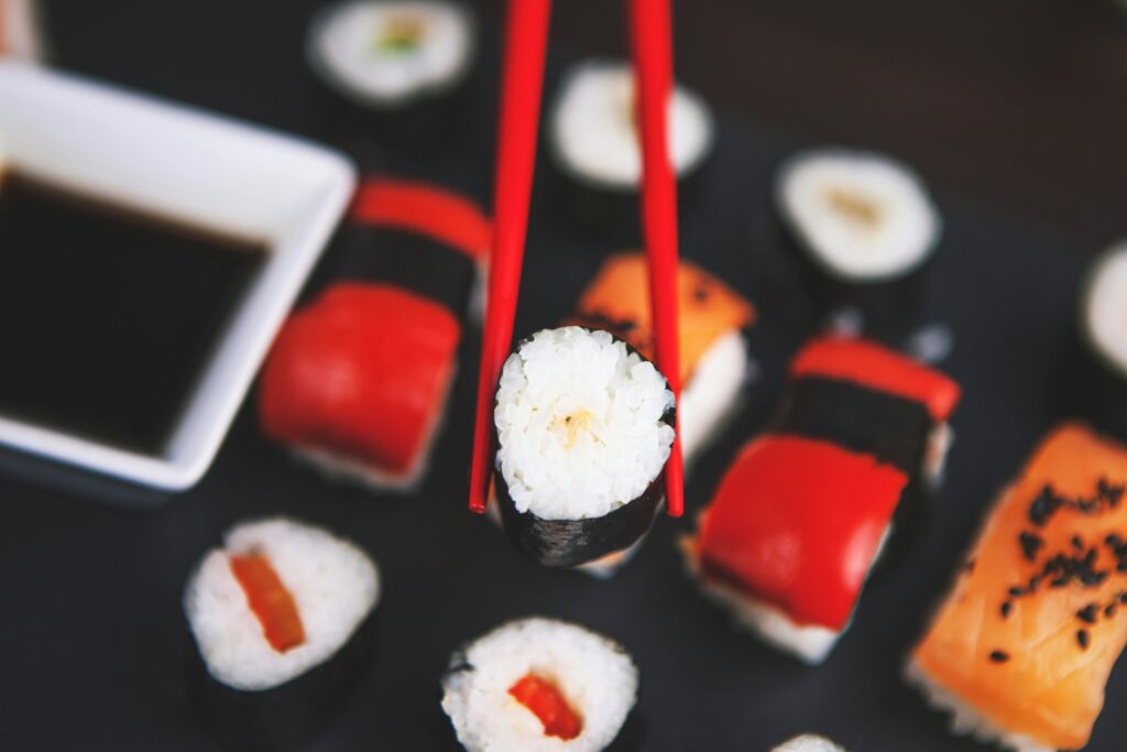 pexels-photo-539430-539430 A selection of various sushi rolls with chopsticks on a dark plate, featuring vivid colors and fresh ingredients.